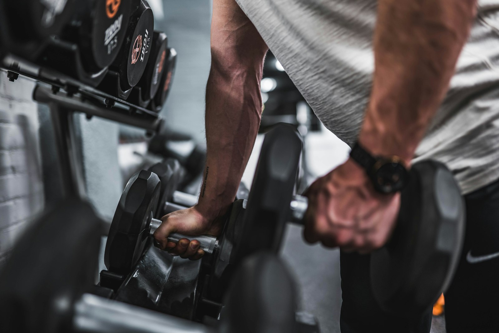 Man training with dumbbells in a gym, focused and mid set